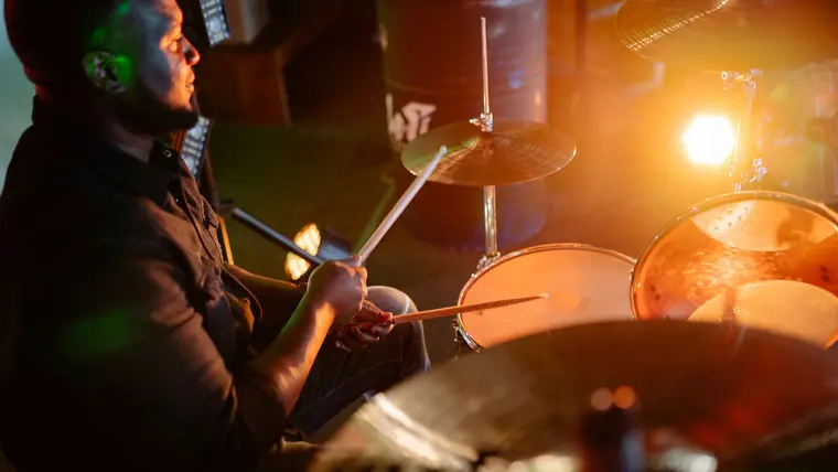 Baterista tocando la batería con luz cálida de escenario