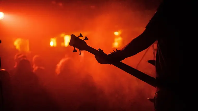 Silueta de un bajista en un concierto de metal con luz roja