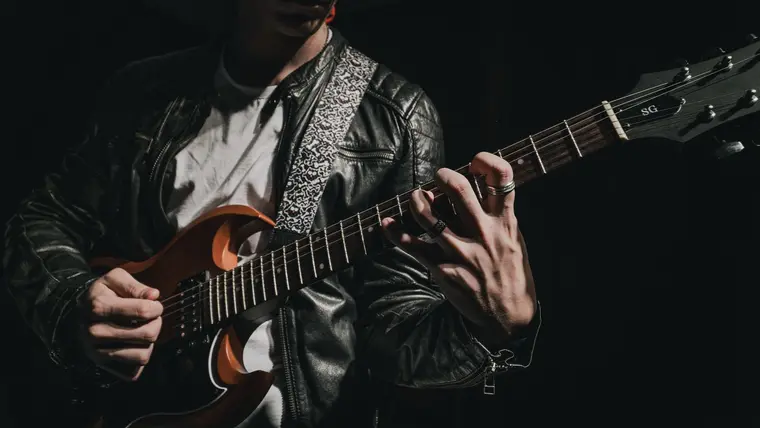 Guitarrista tocando una guitarra eléctrica en un ambiente oscuro
